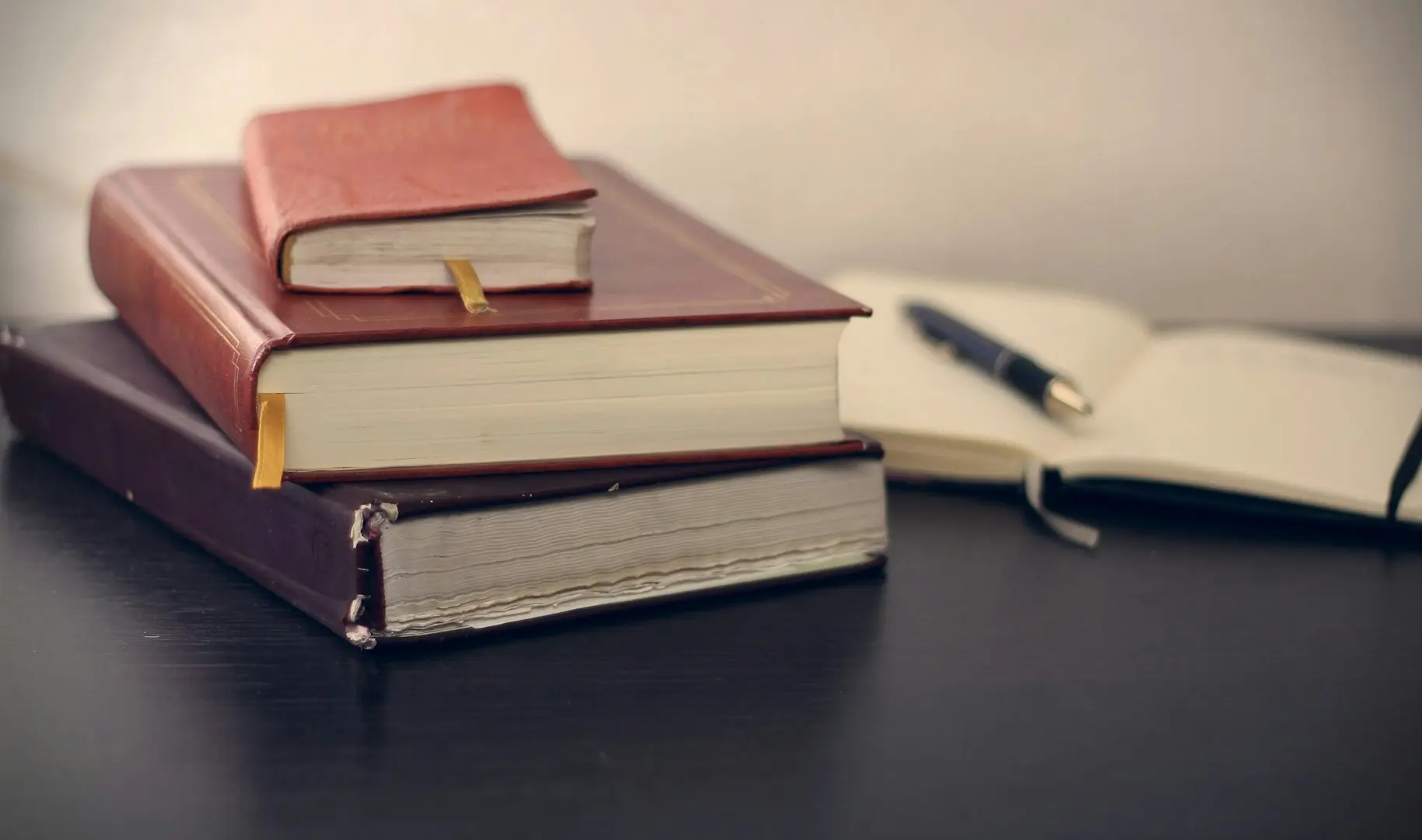 selective focus photography of three books beside opened notebook